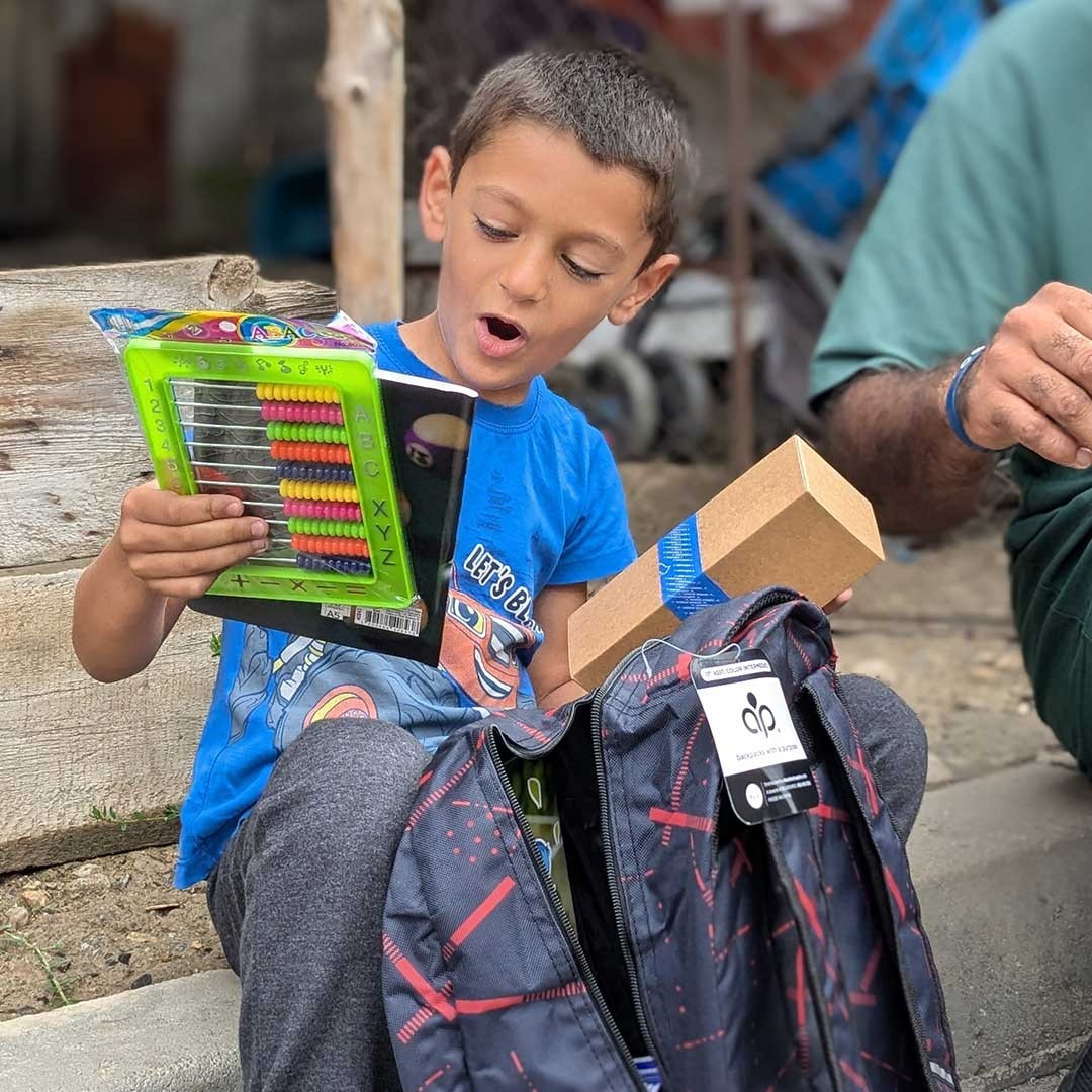 A boy smiles as he looks through his new school supplies.