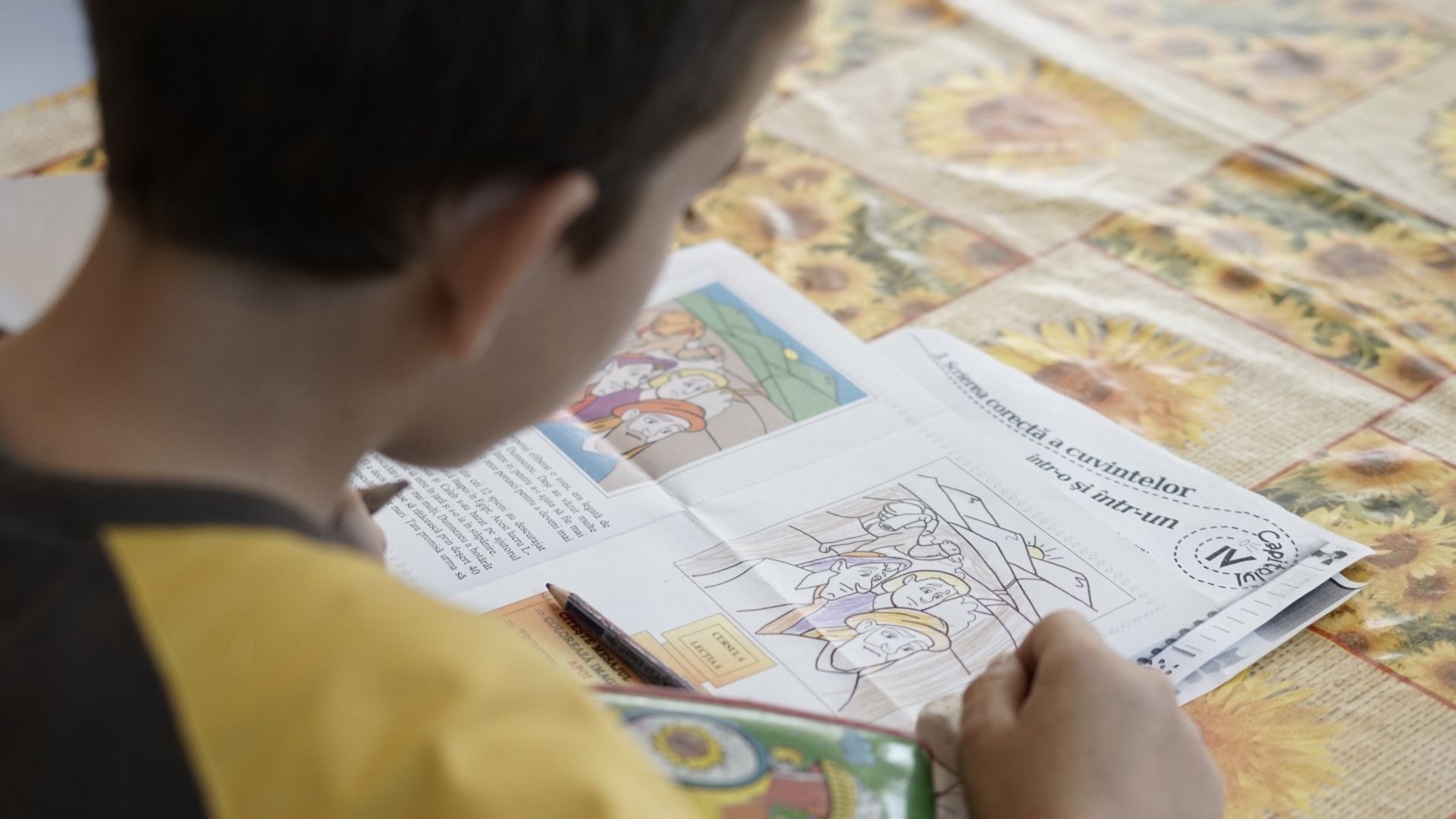 Boy in a black and yellow shirt focused on a Bible lesson activity.