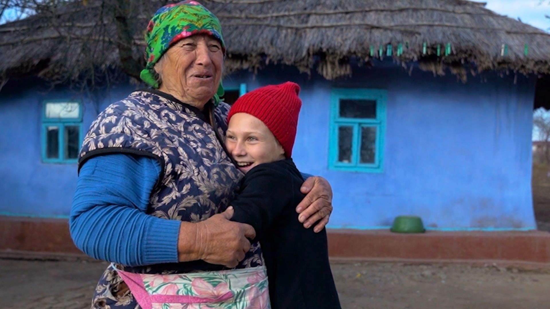 Helena and Patricia in a warm and joyful embrace outside their home