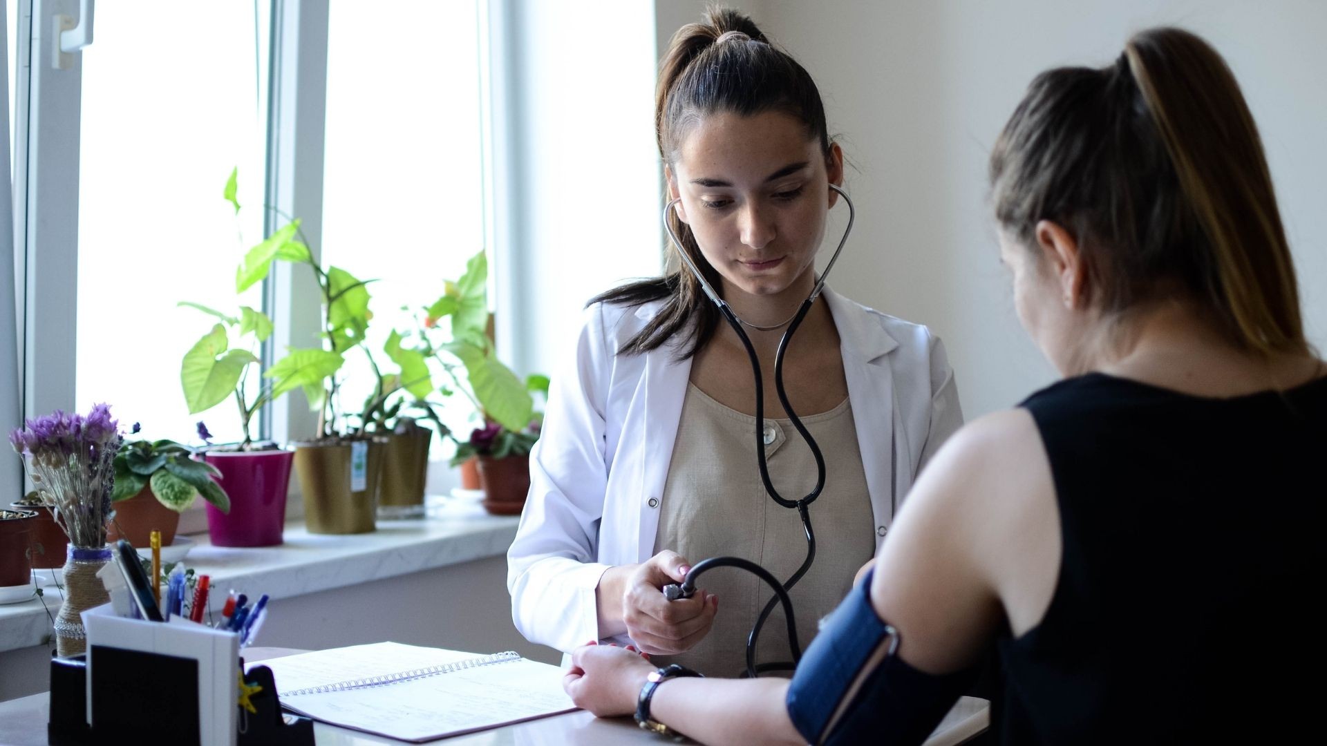 Young female doctor using a stethoscope to listen to a patient’s heartbeat.