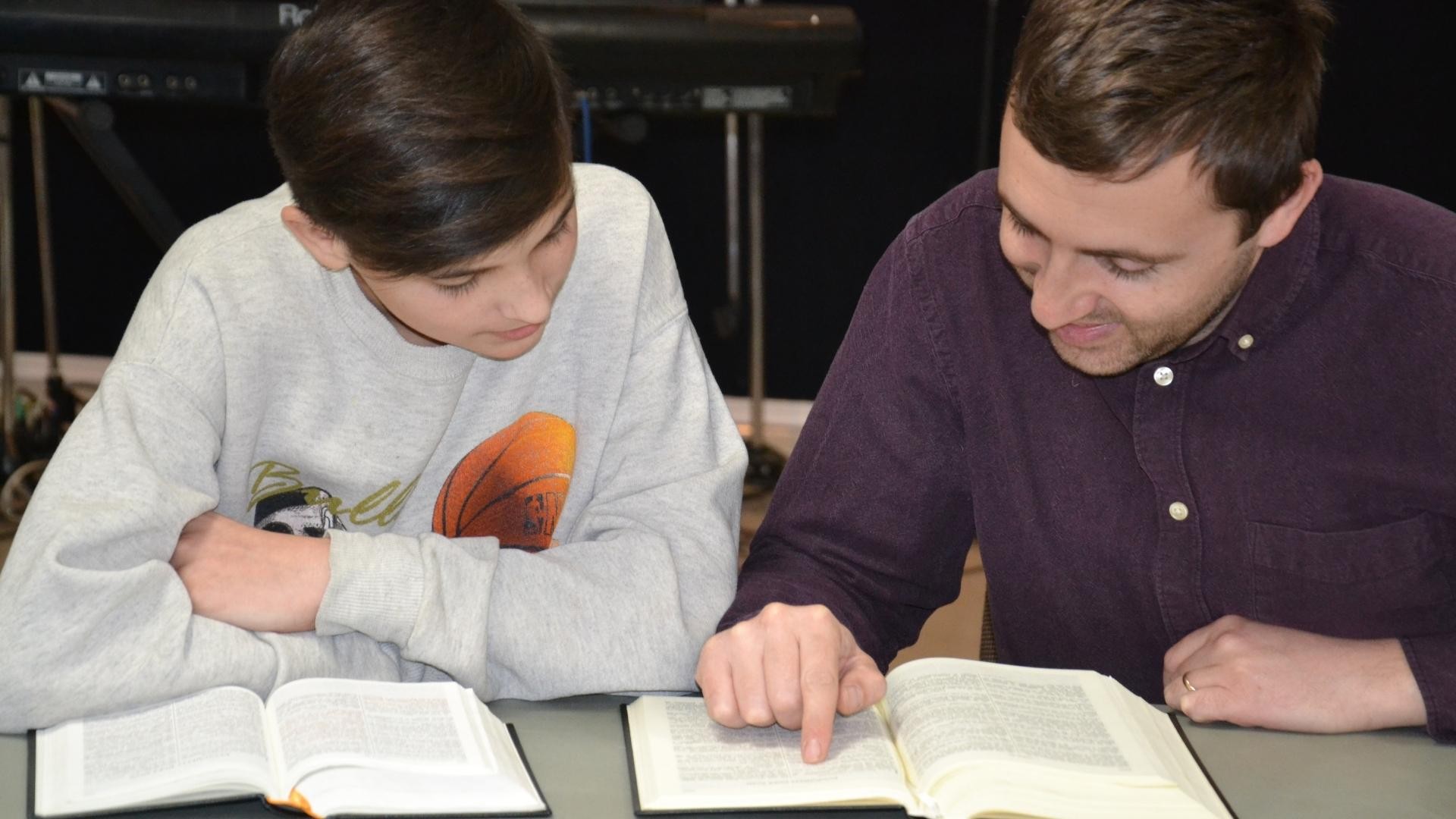 Two young men read a Bible together.