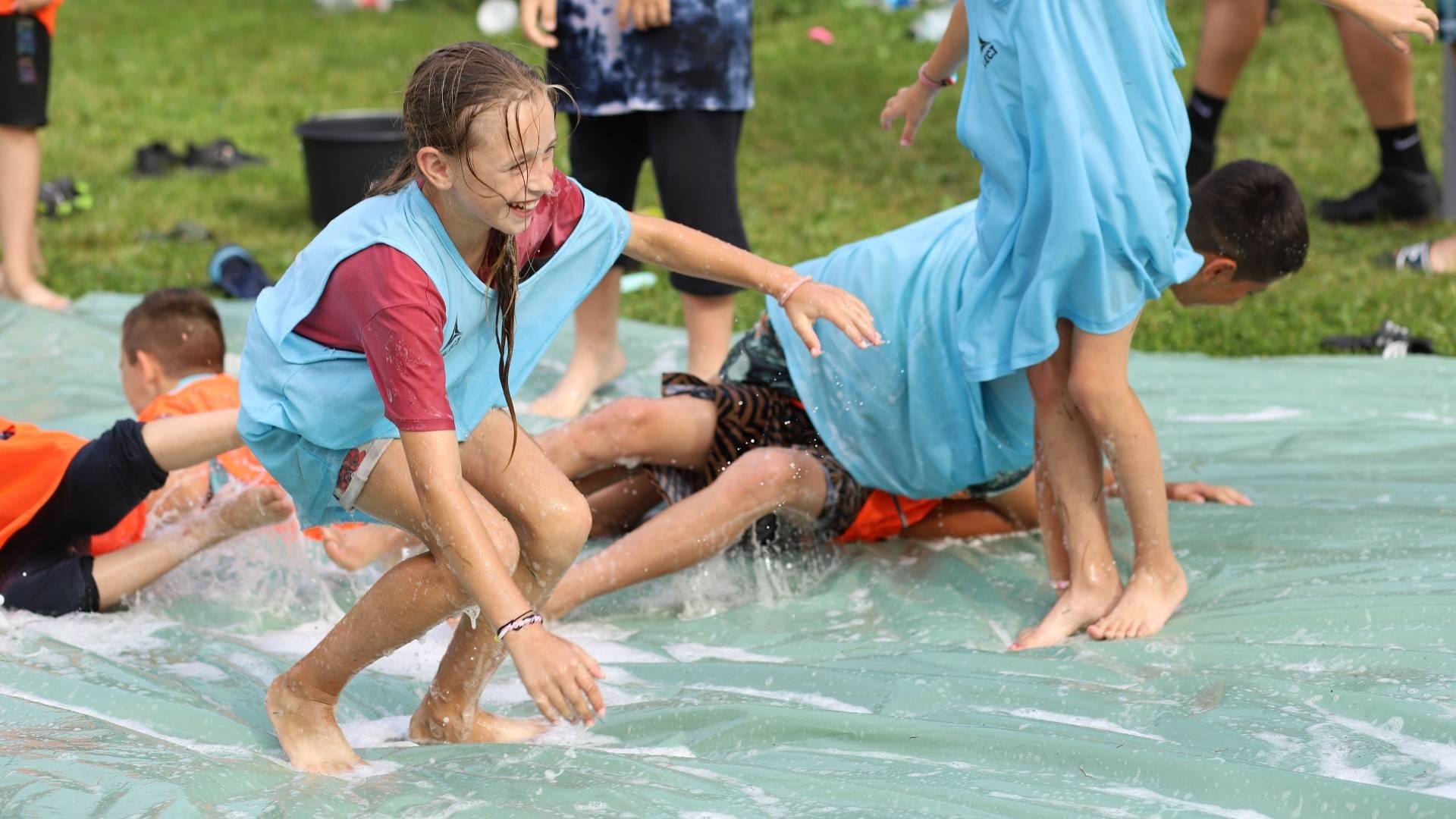 Children laugh and play together, enjoying fun on a water slide.