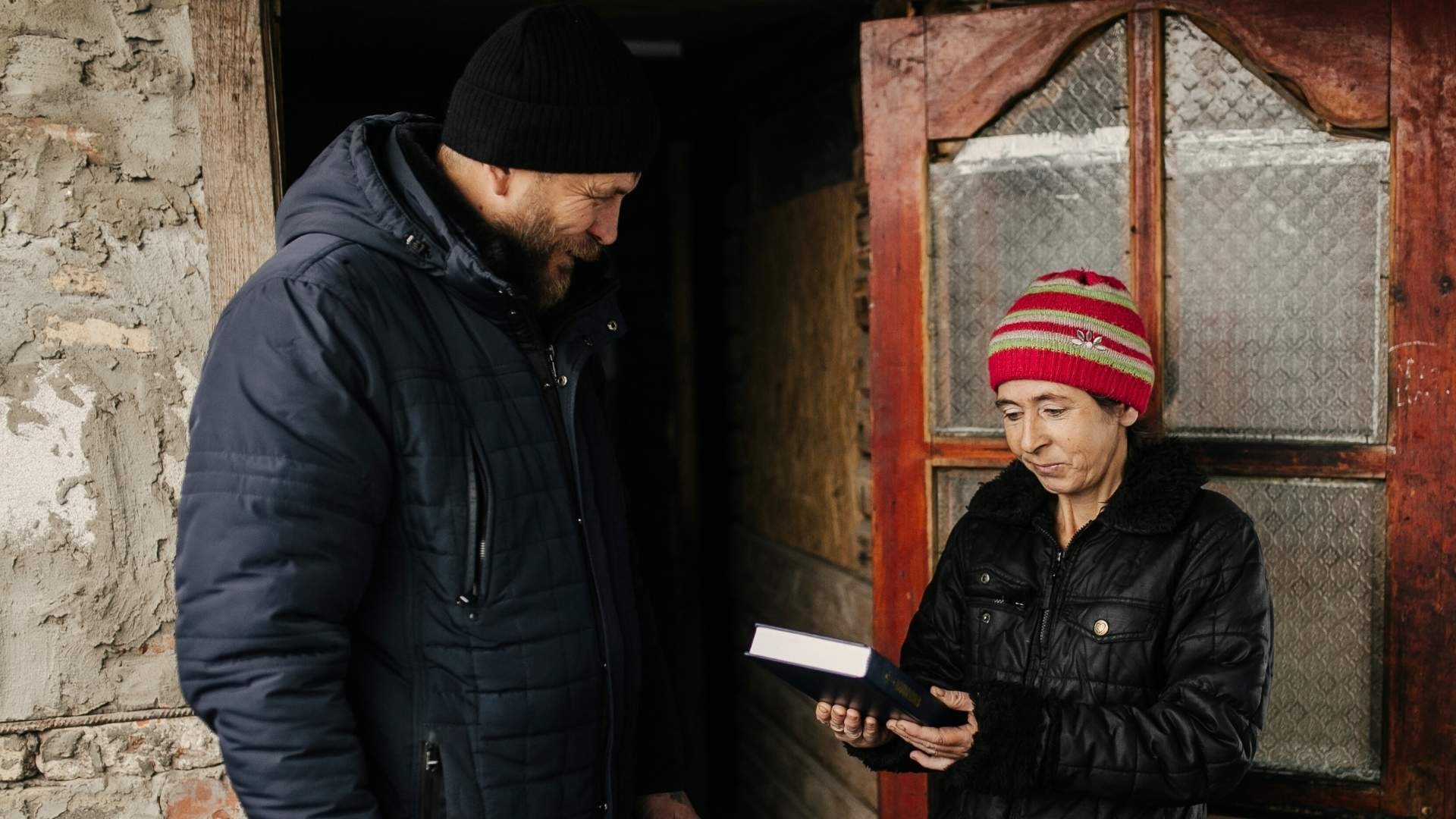 Grateful woman receiving a Bible from a man standing beside her.