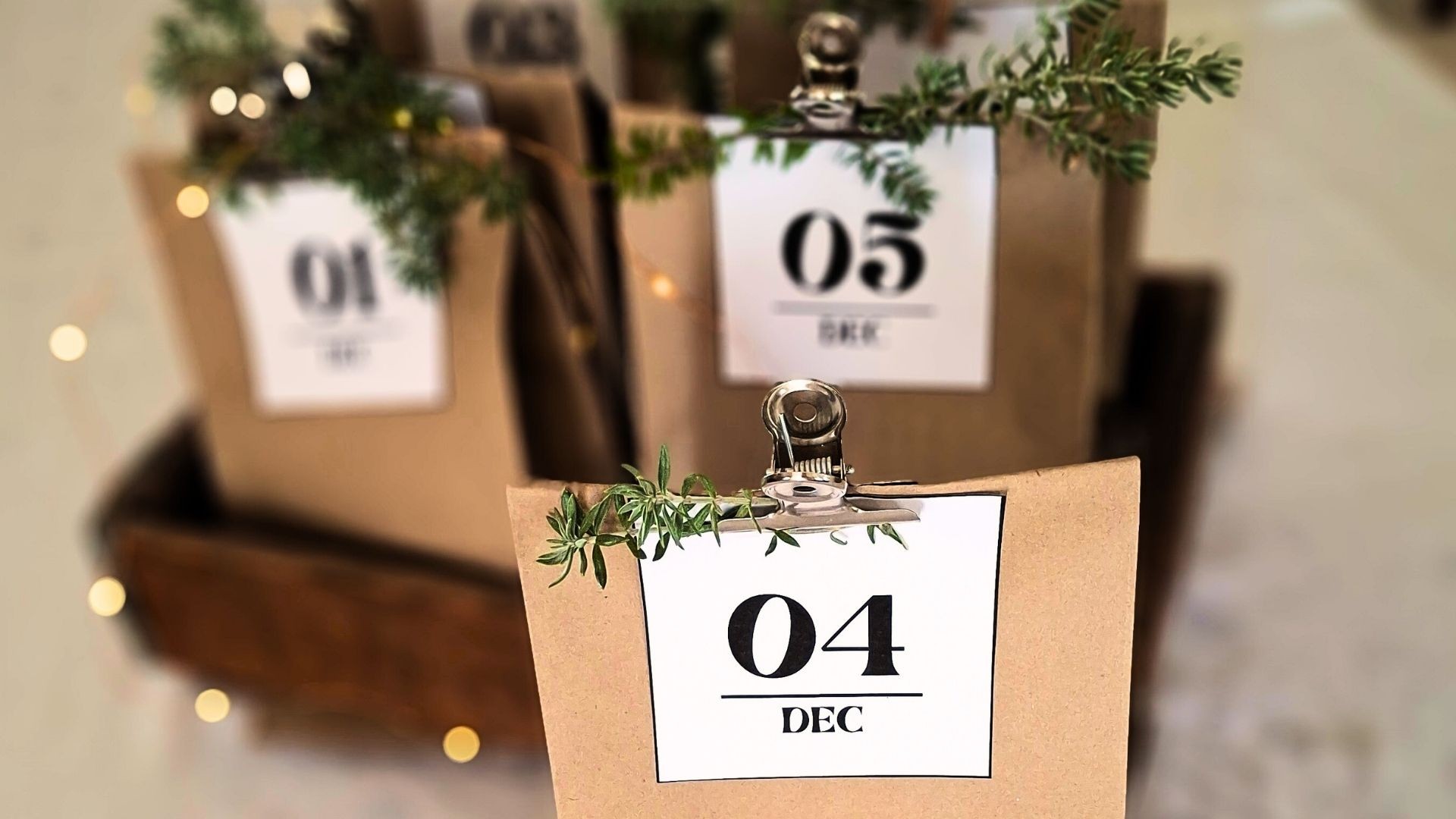 Decorated brown paper bags labeled with dates, arranged with festive Christmas greenery.