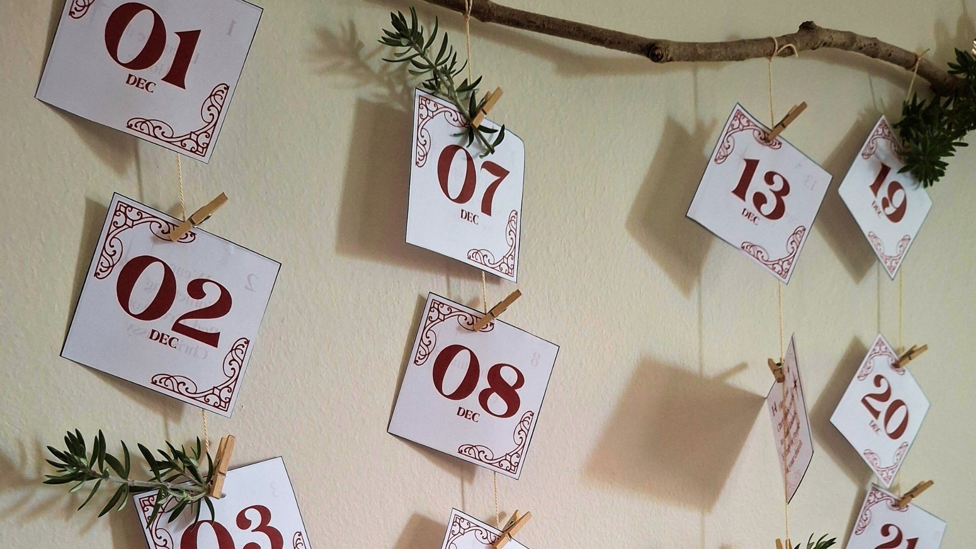 Advent date cards pinned to a string and decorated with festive greenery.