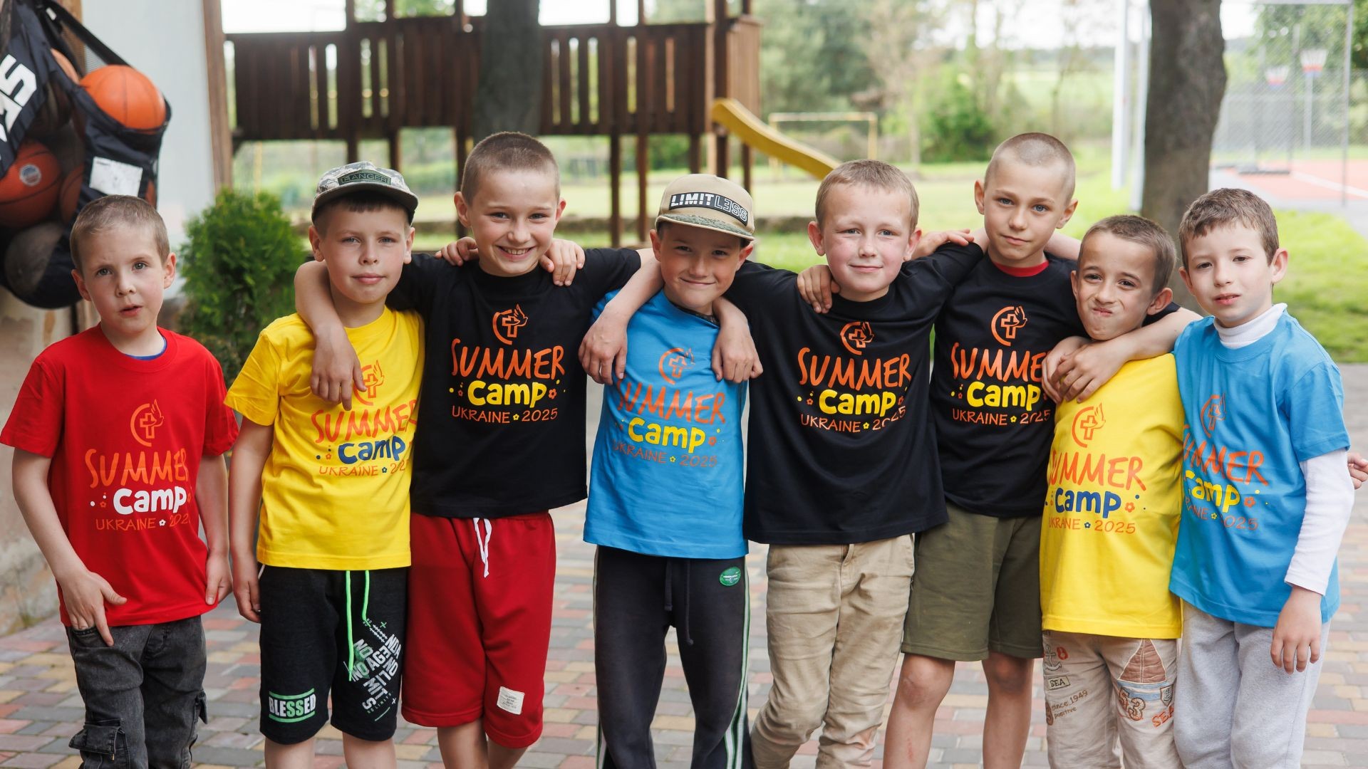 A group of young boys wearing colorful Ukraine camp t-shirts, standing together and smiling.