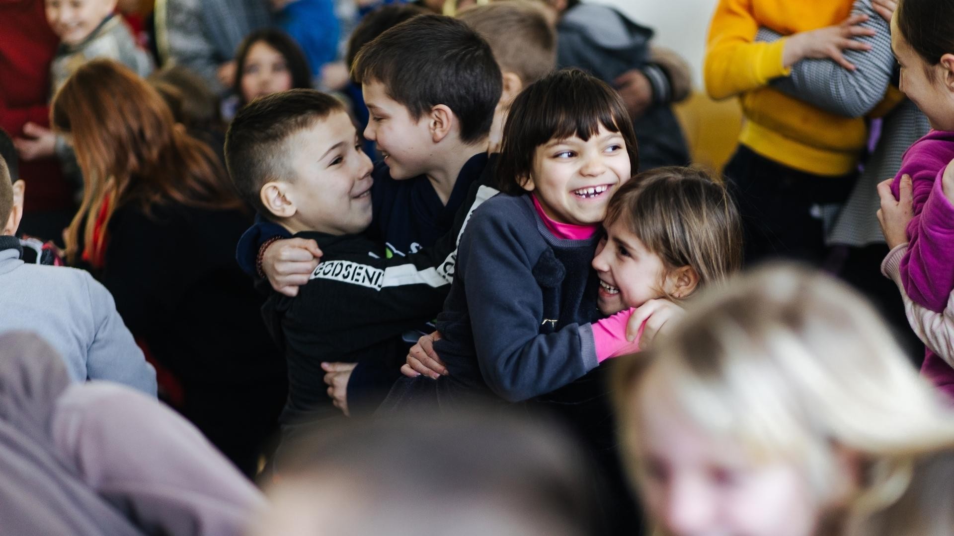 Multiple children joyfully hugging each other.