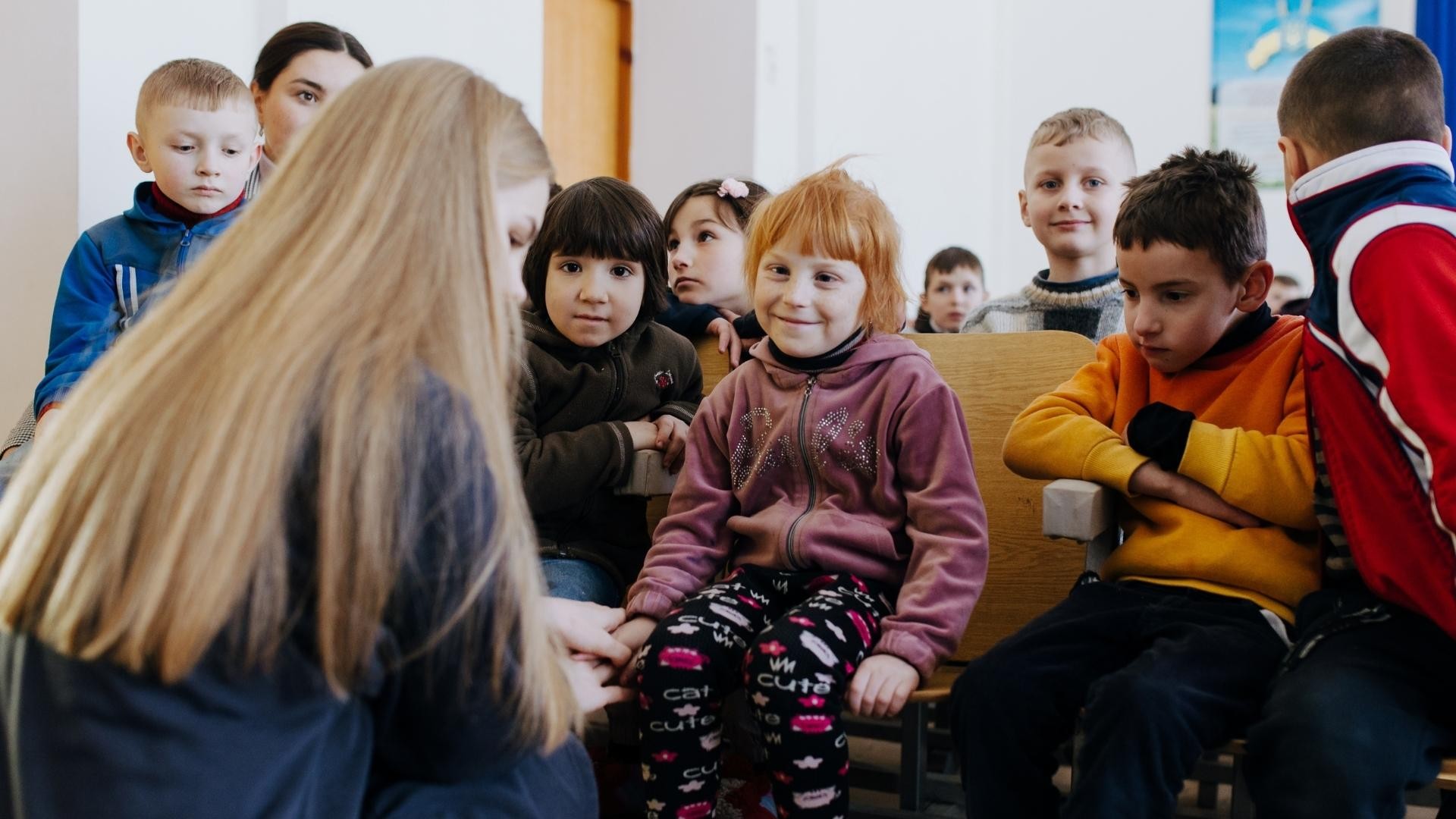 Smiling red-haired girl looking at an adult kneeling in front of her.