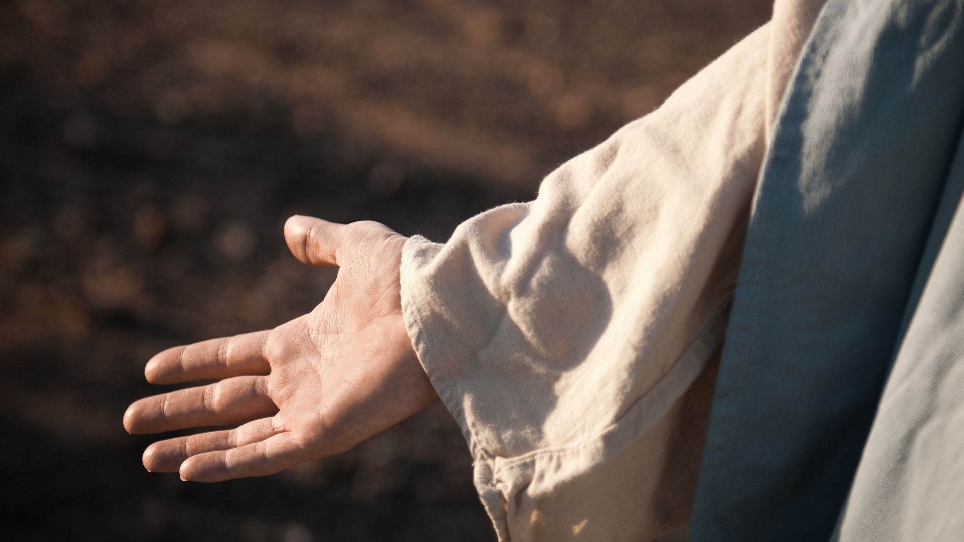 Open hand in flowing Middle Eastern clothing gestures gently.