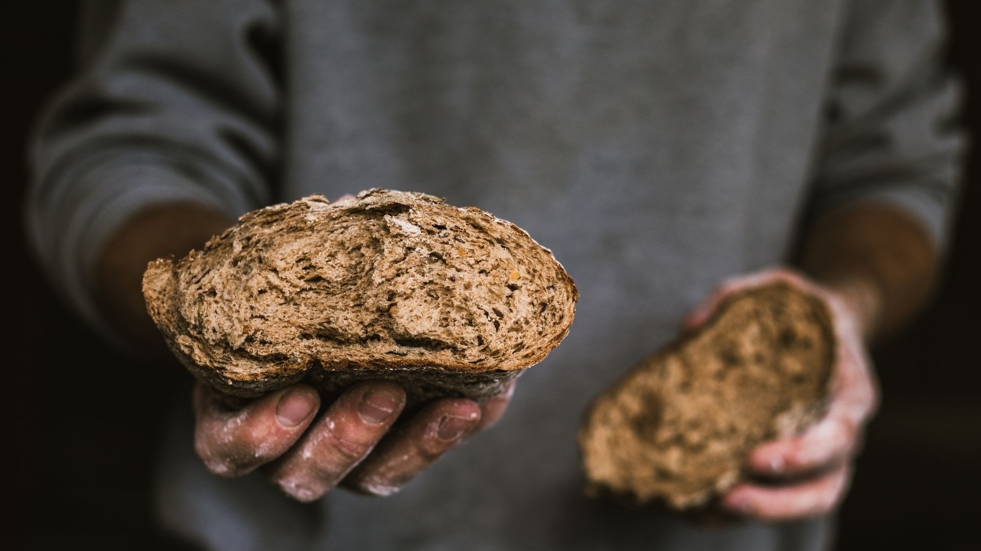 Man holds out a piece of broken bread