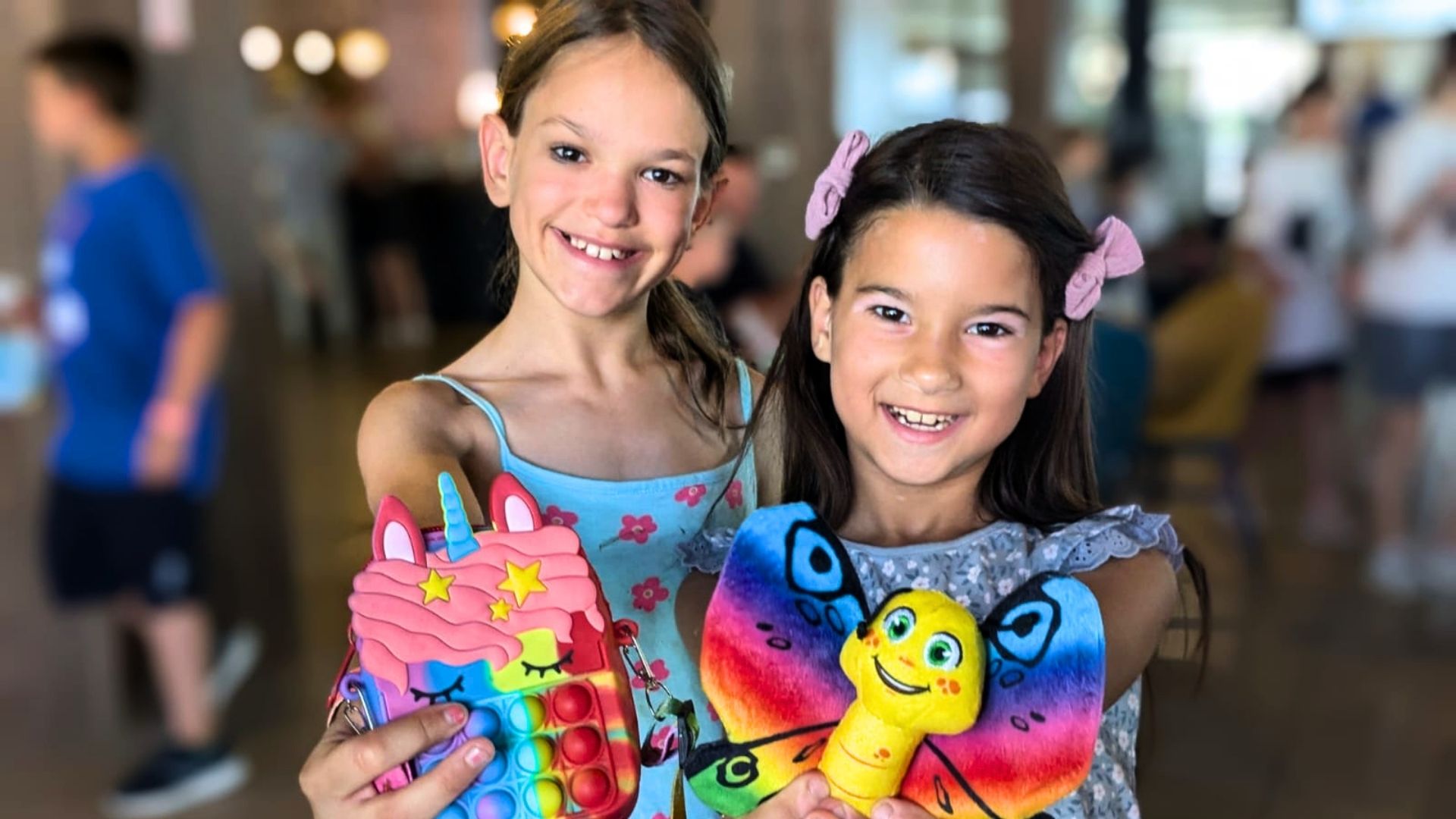 Two young girls holding up gifts with big smiles.