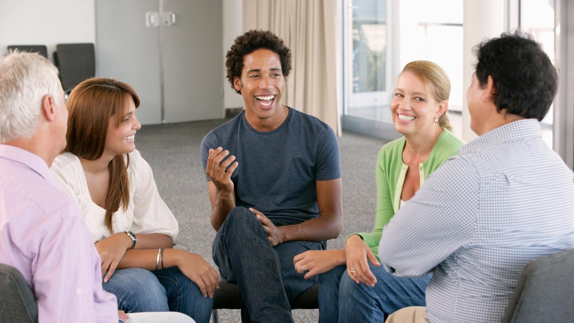 Group of people sit together, sharing in a friendly discussion.