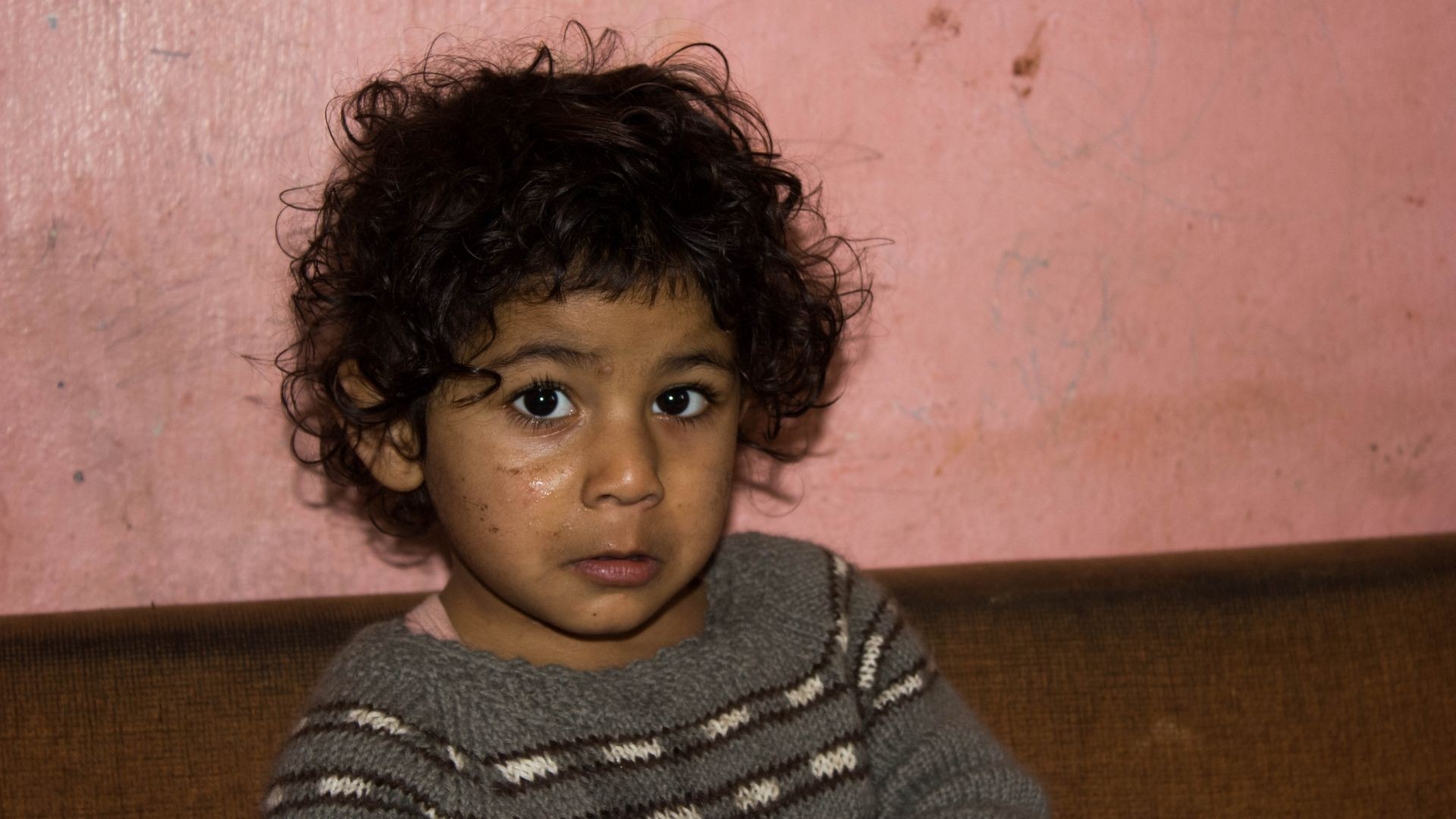Roma boy with a quivering lip, appearing on the verge of crying.