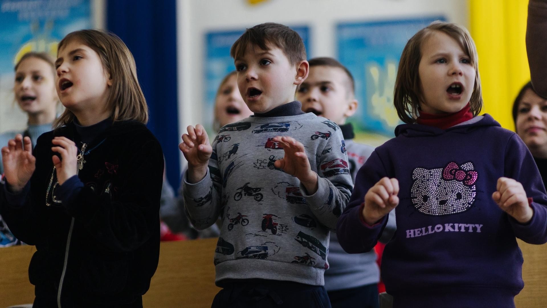 Children sing and act out a song together.