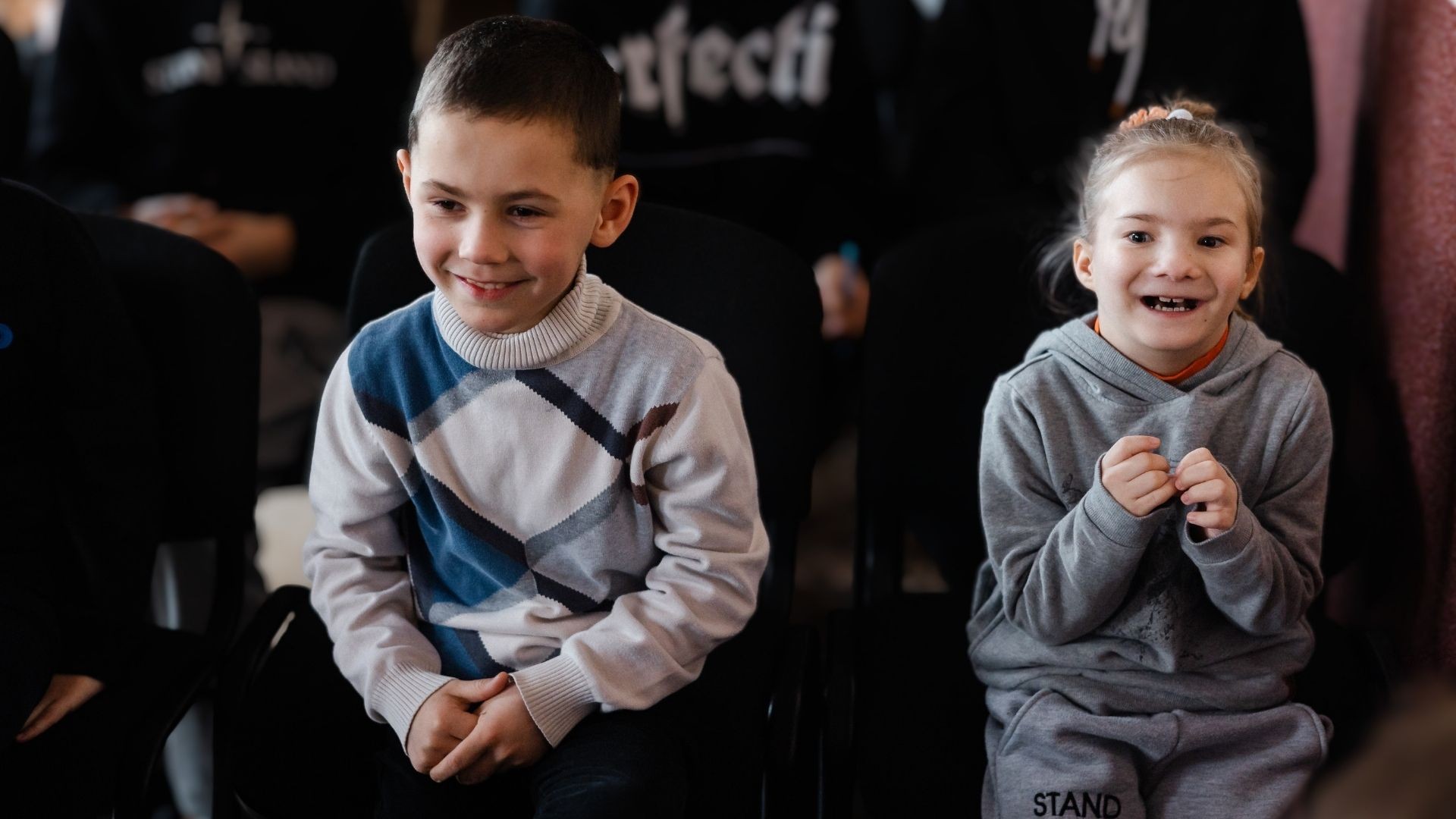 Young boy and girl laugh as they enjoy a children's gathering.