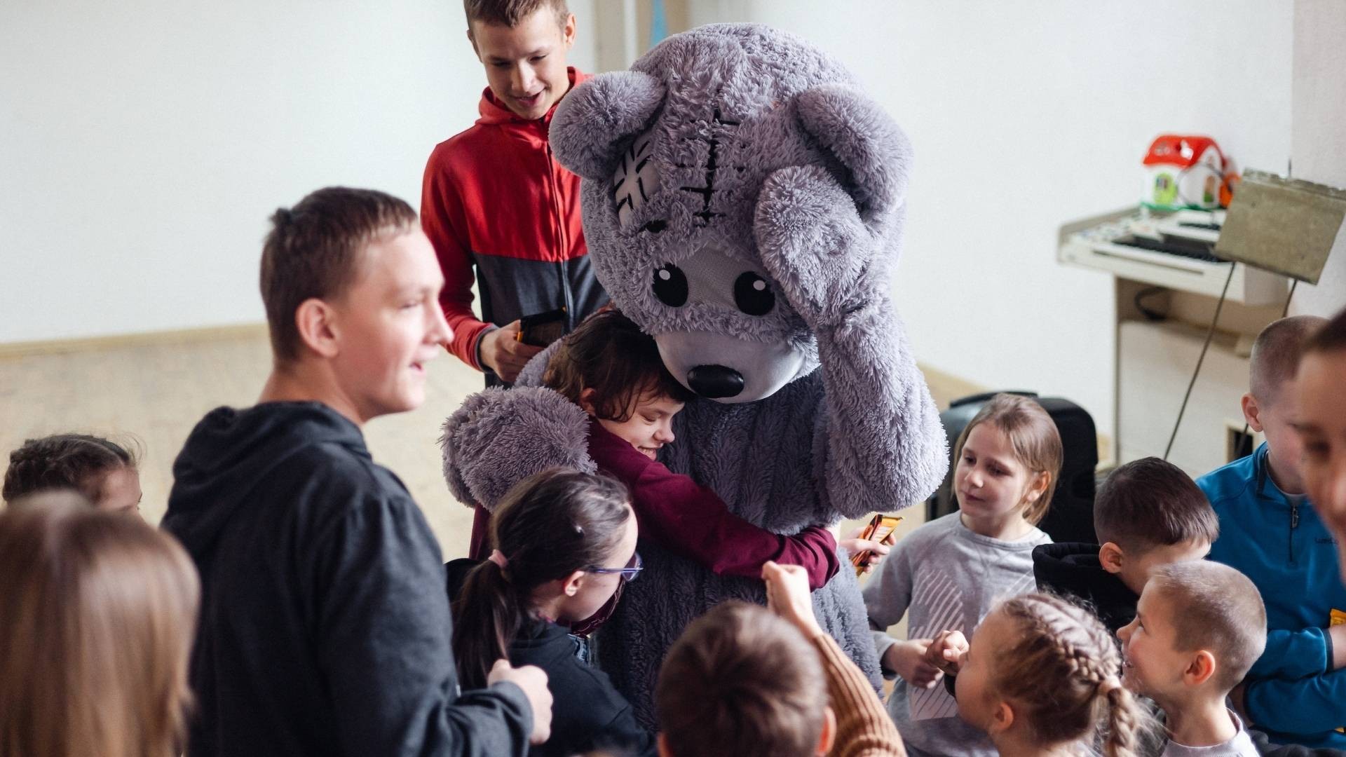 Upanchik, the large grey bear, surrounded by children eager to hug him.