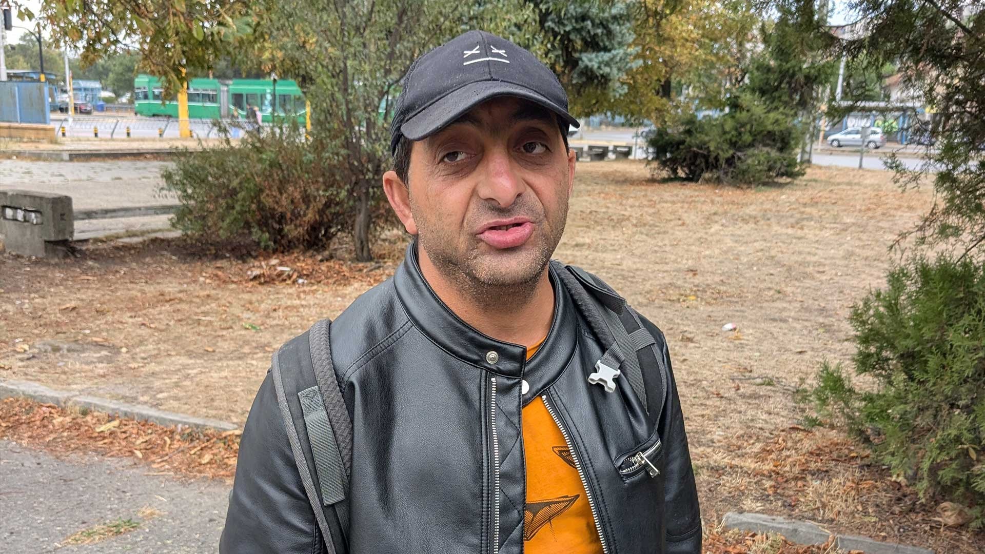 A middle-aged man wearing a cap and a leather jacket, speaking during a conversation.