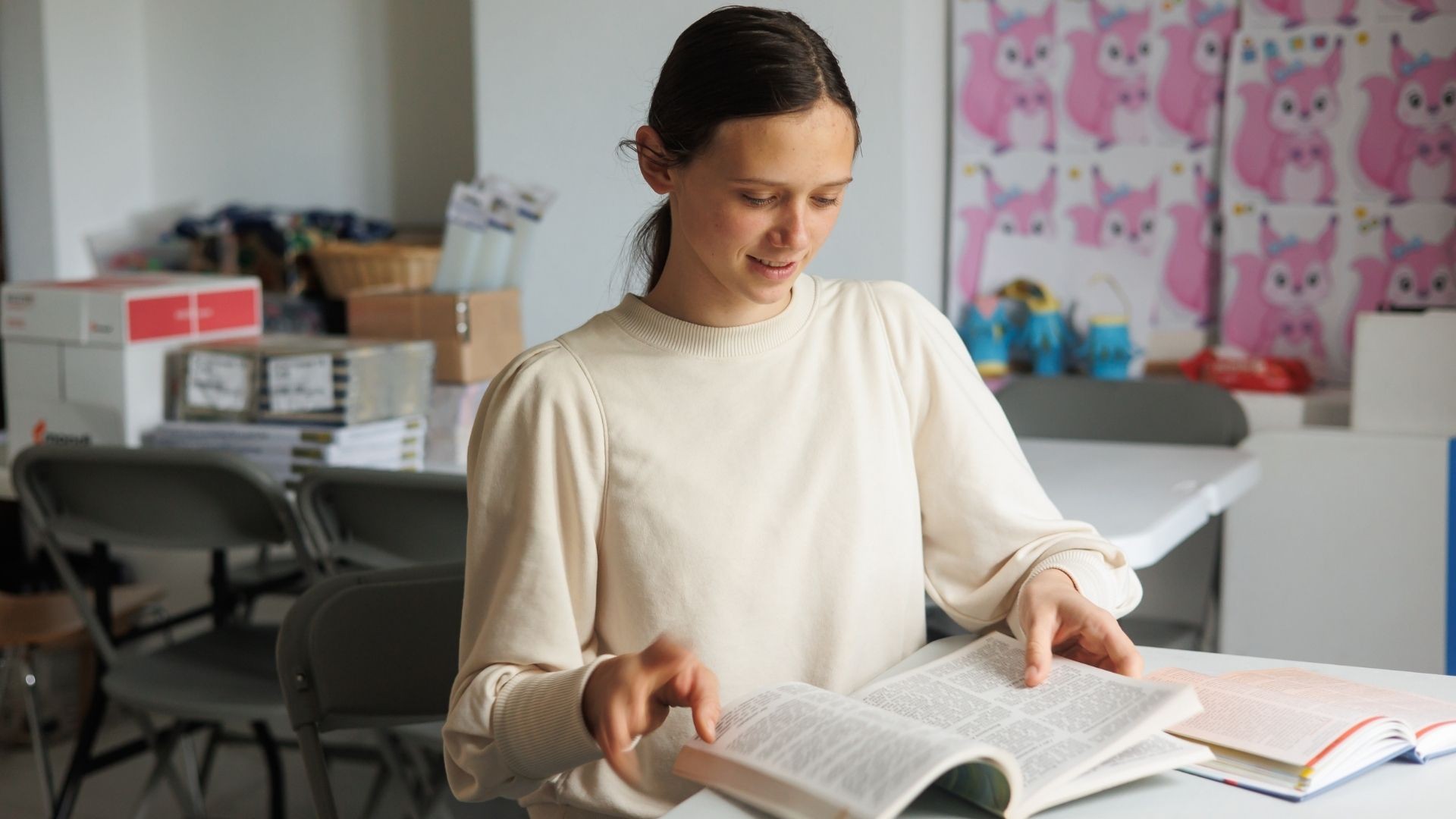 Maryna sits at a desk, smiling at an open Bible, her long dark hair tied back in a ponytail