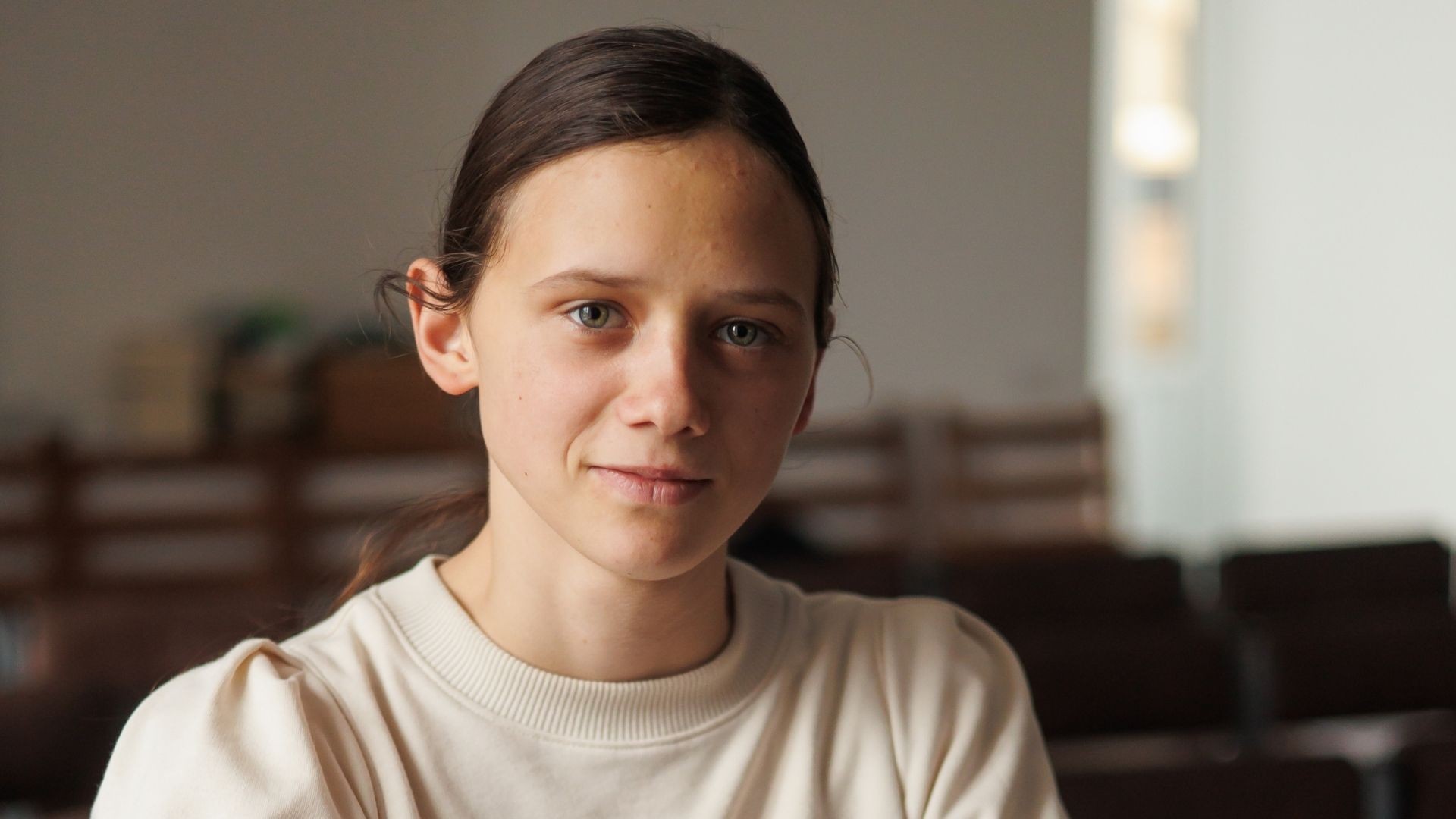 Maryna sits quietly, faint smile on her face, long dark hair tied back