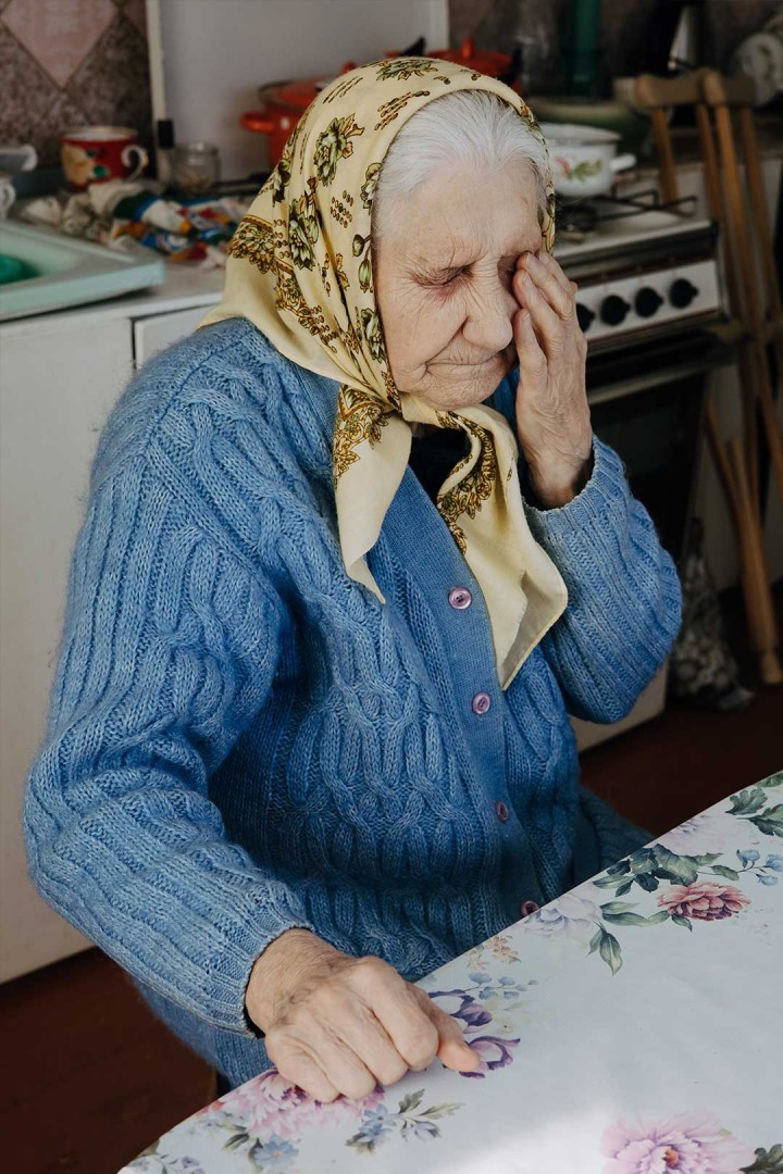 Tired and elderly, widow Galyna rubs her eye
