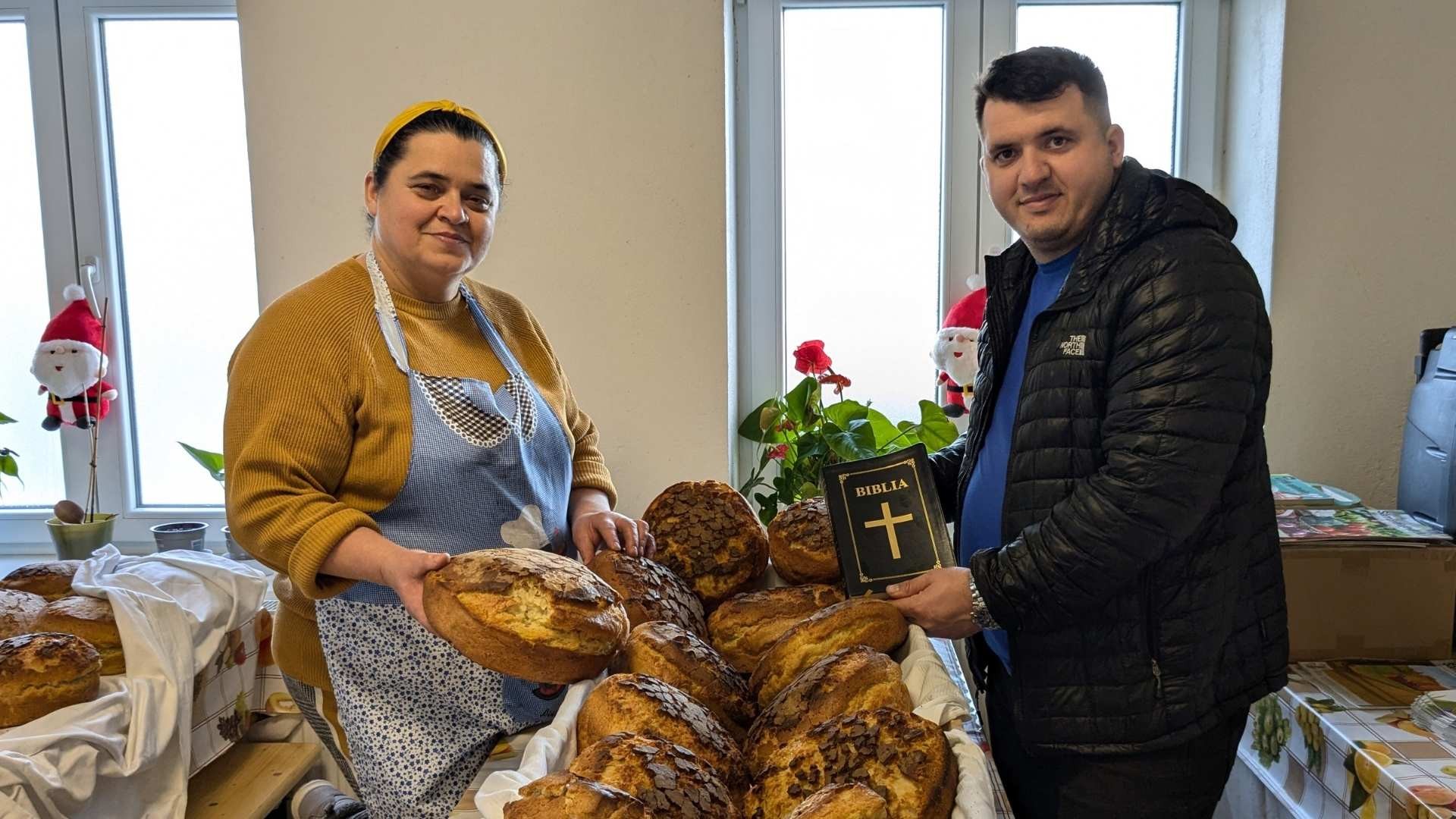 Maria and Cosmin hold freshly baked bread and a Bible