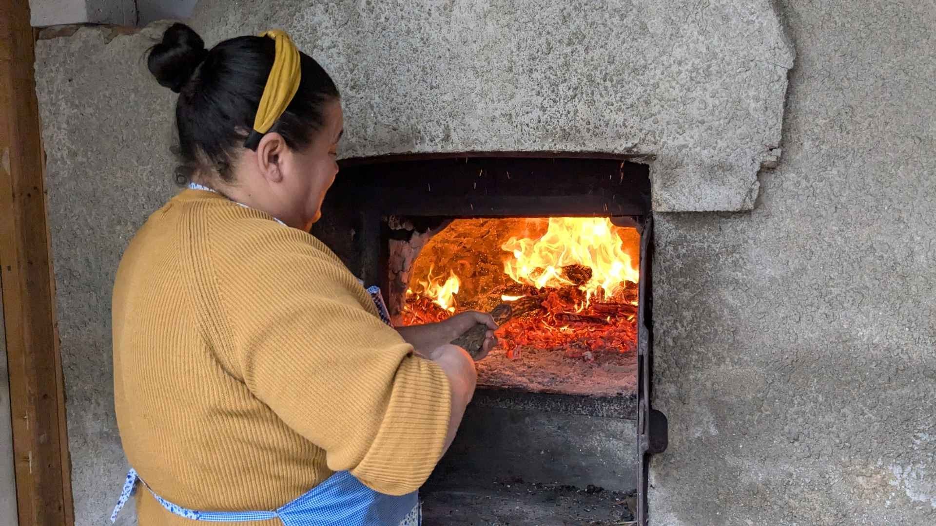 Maria checks the wood-fired oven, ensuring the bread bakes perfectly