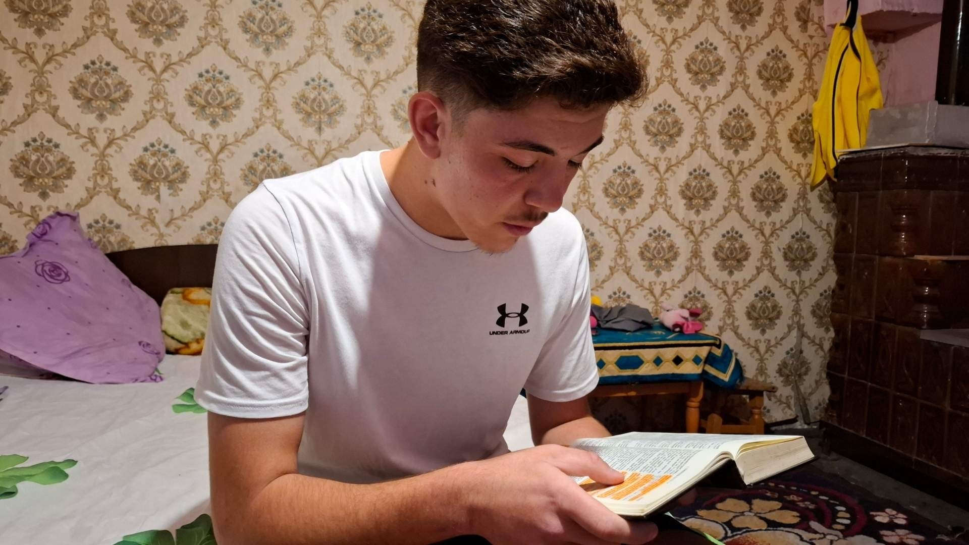 Teenage boy reading a highlighted passage in his bible.