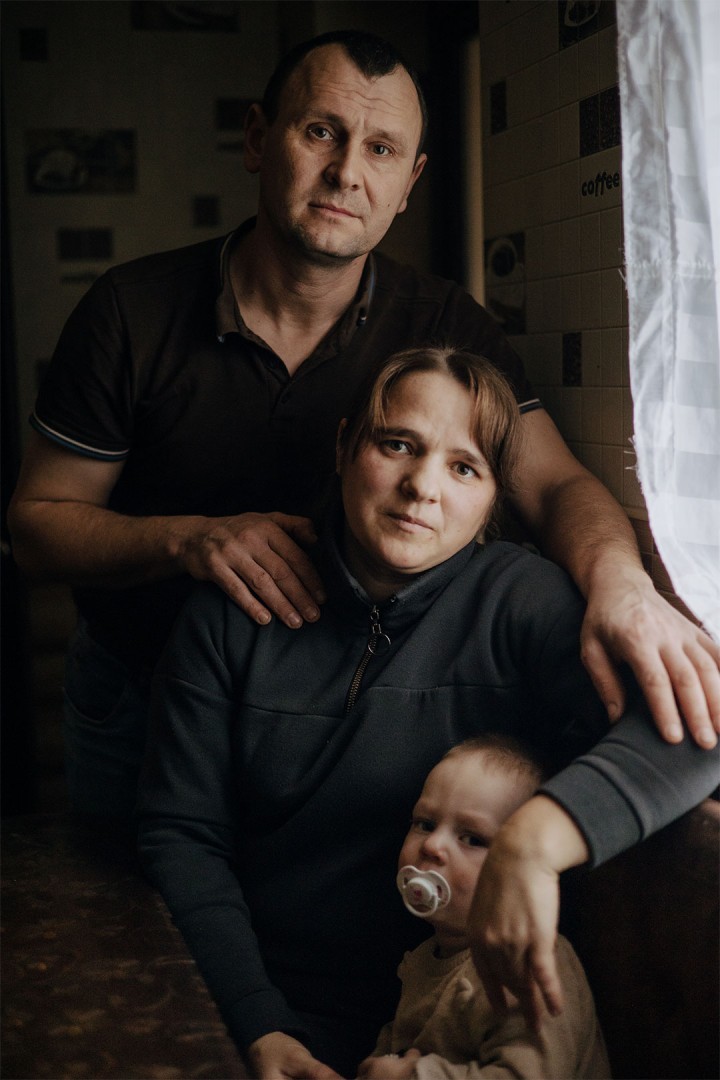 Iryna sits with her husband and baby inside their home