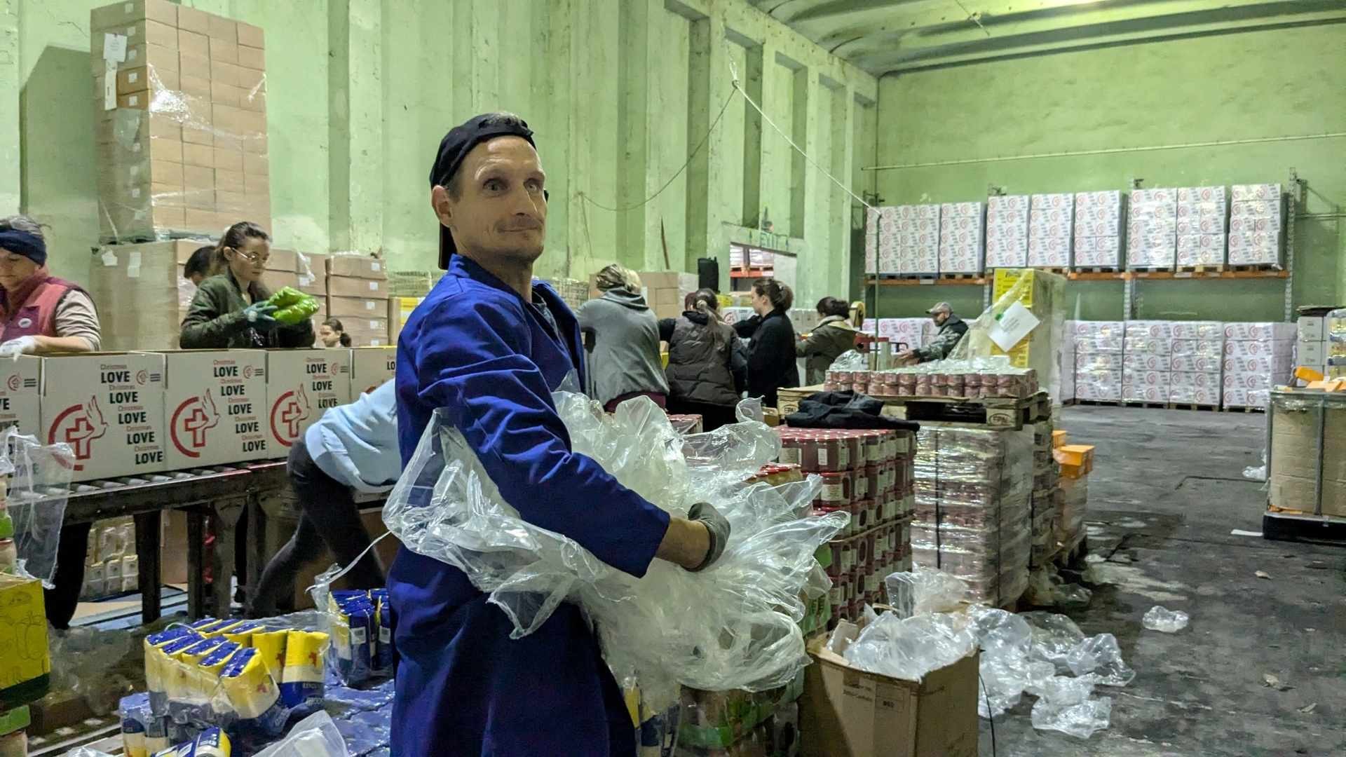 a middle-aged man holding packing material in a warehouse.