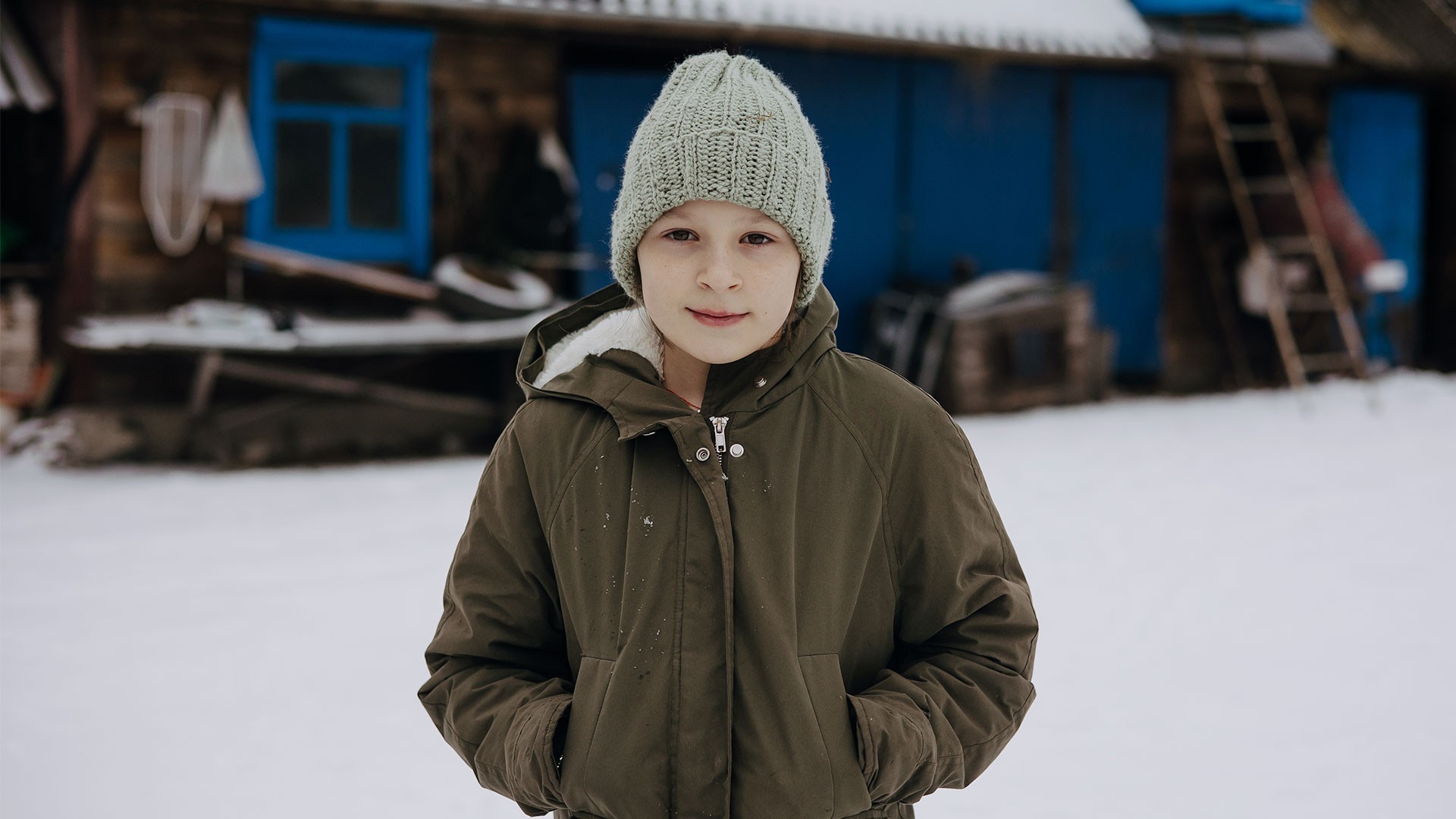 Young Sofiya stands outside in a snow-covered yard.