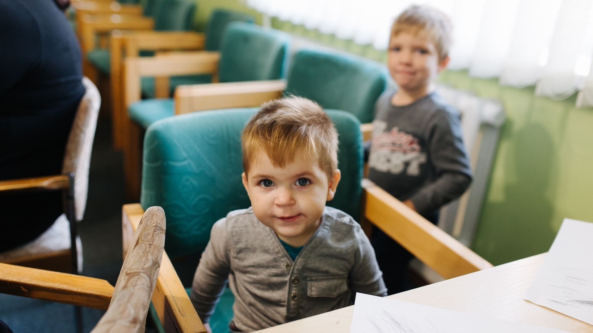 Two young refugee boys play nearby while their mother joins an art therapy session.