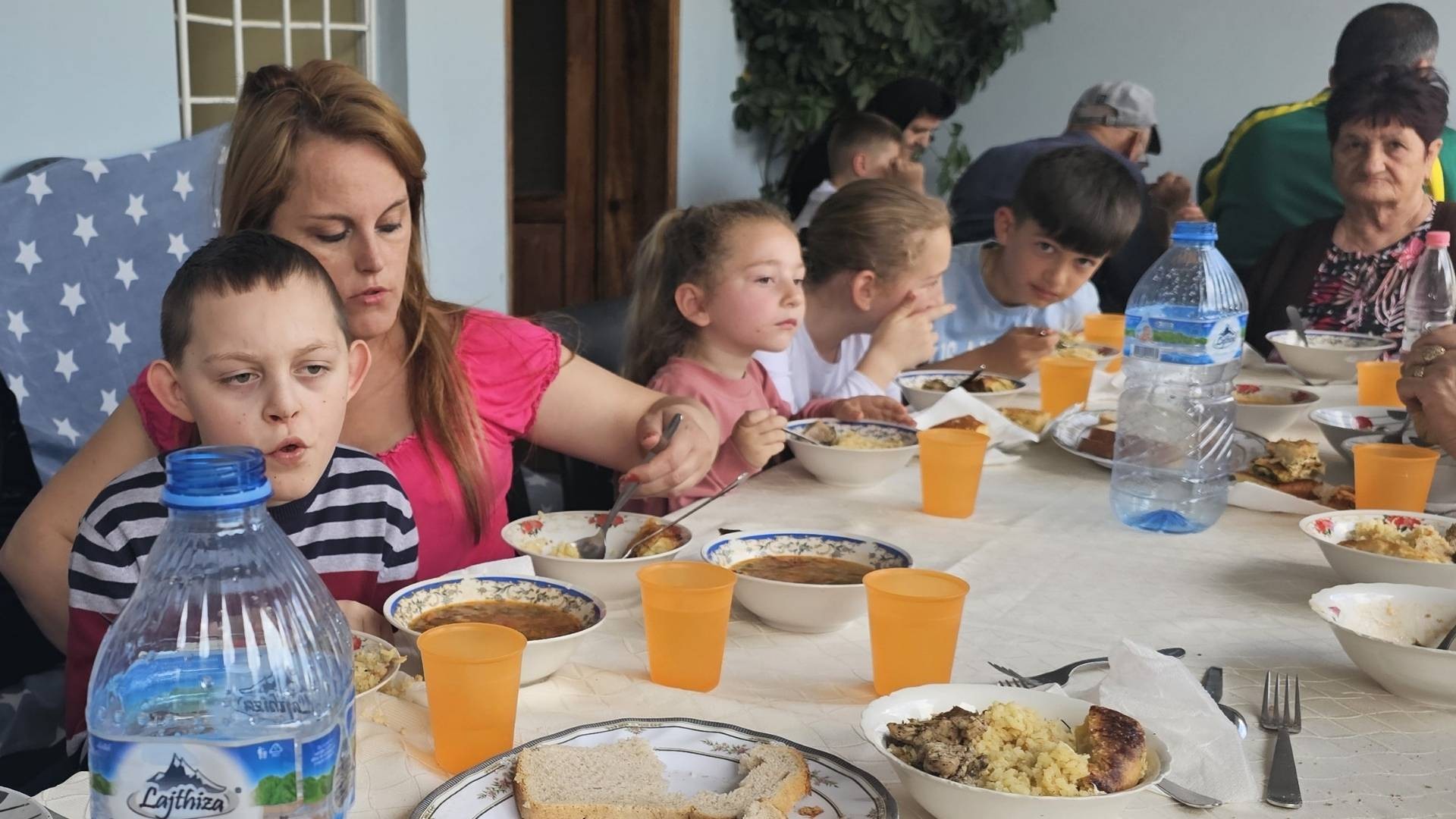 Mother holds her son while eating, seated among others at a soup kitchen.