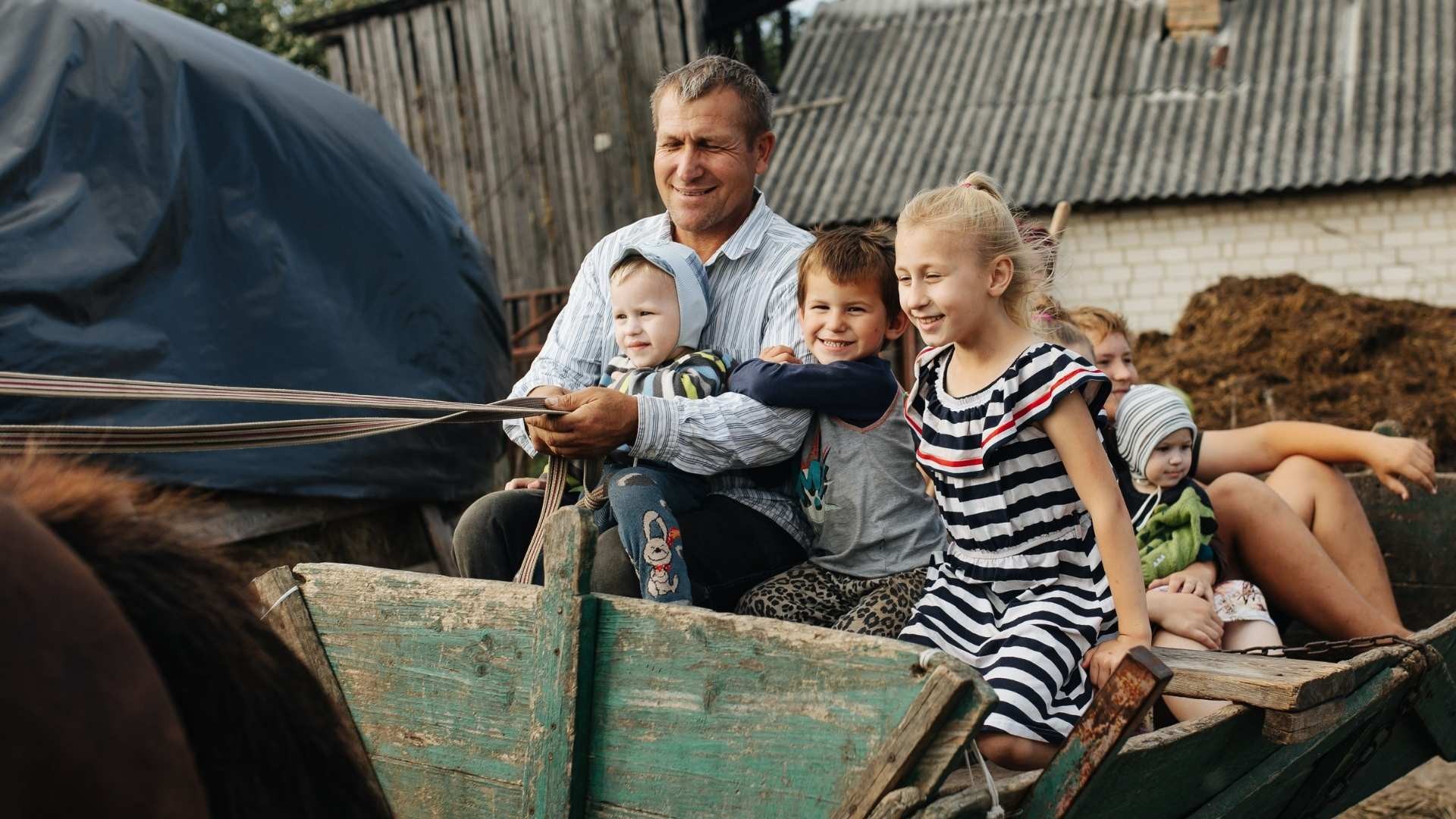 Father steering a horse-drawn cart while his children ride along.