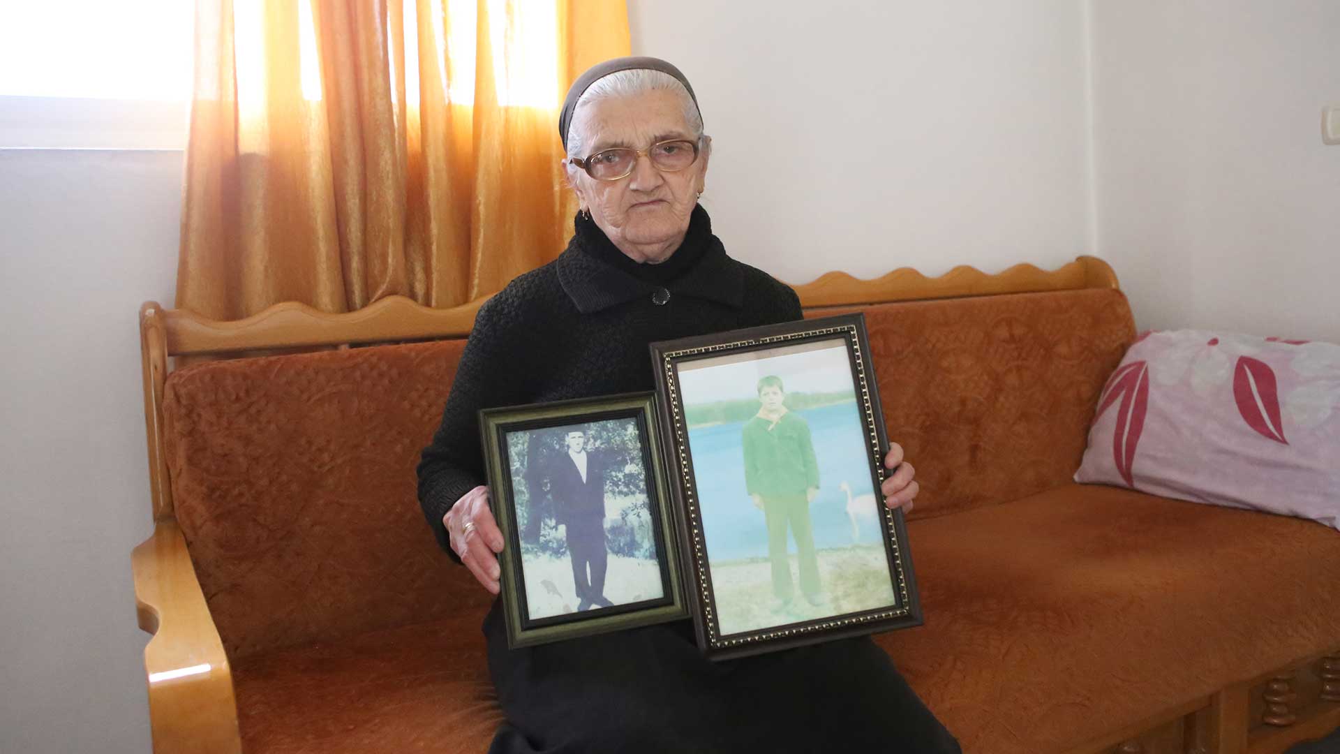 An elderly lady shows photos of her sons.