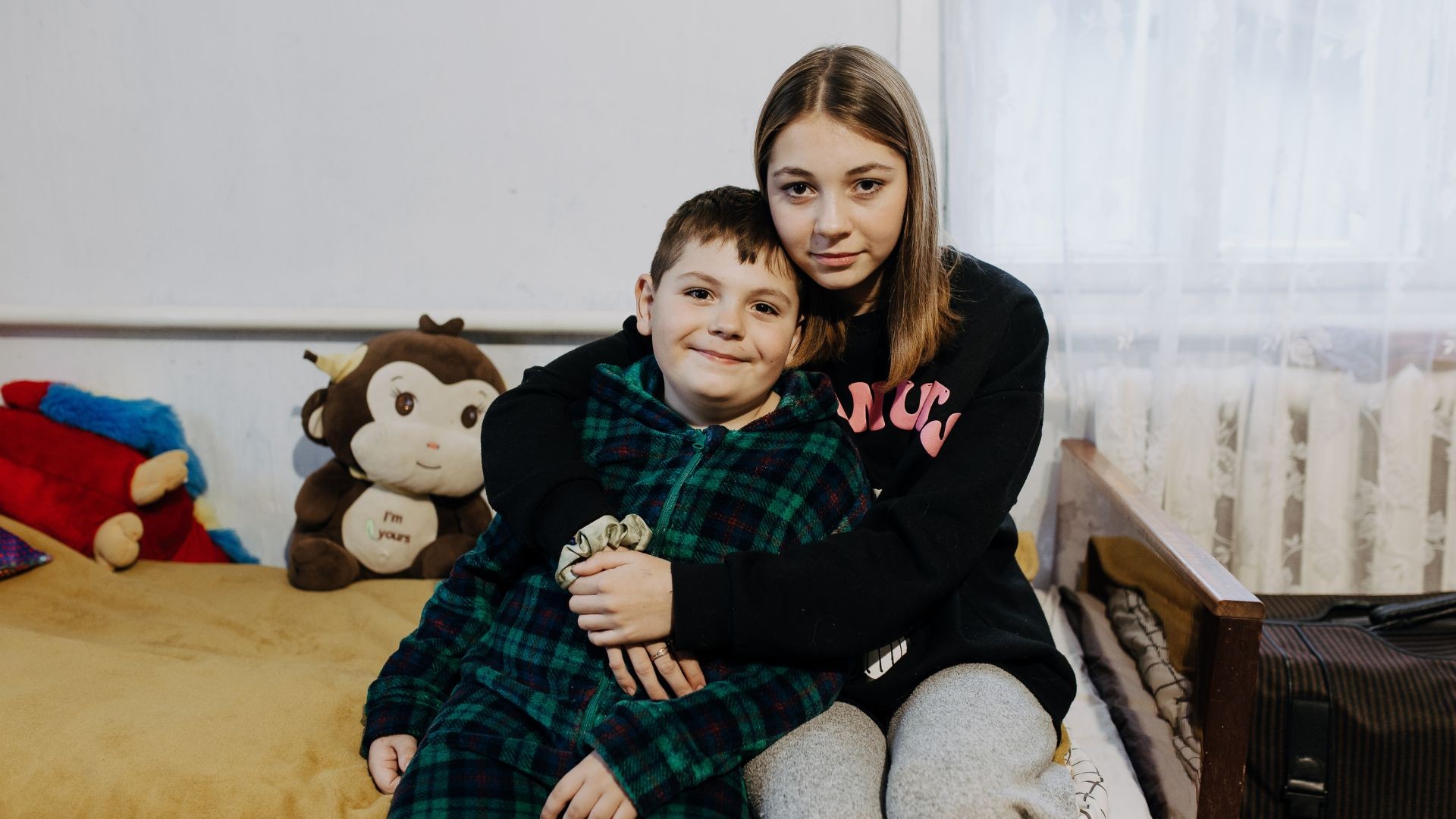 Young boy leaning into embrace of teenage girl